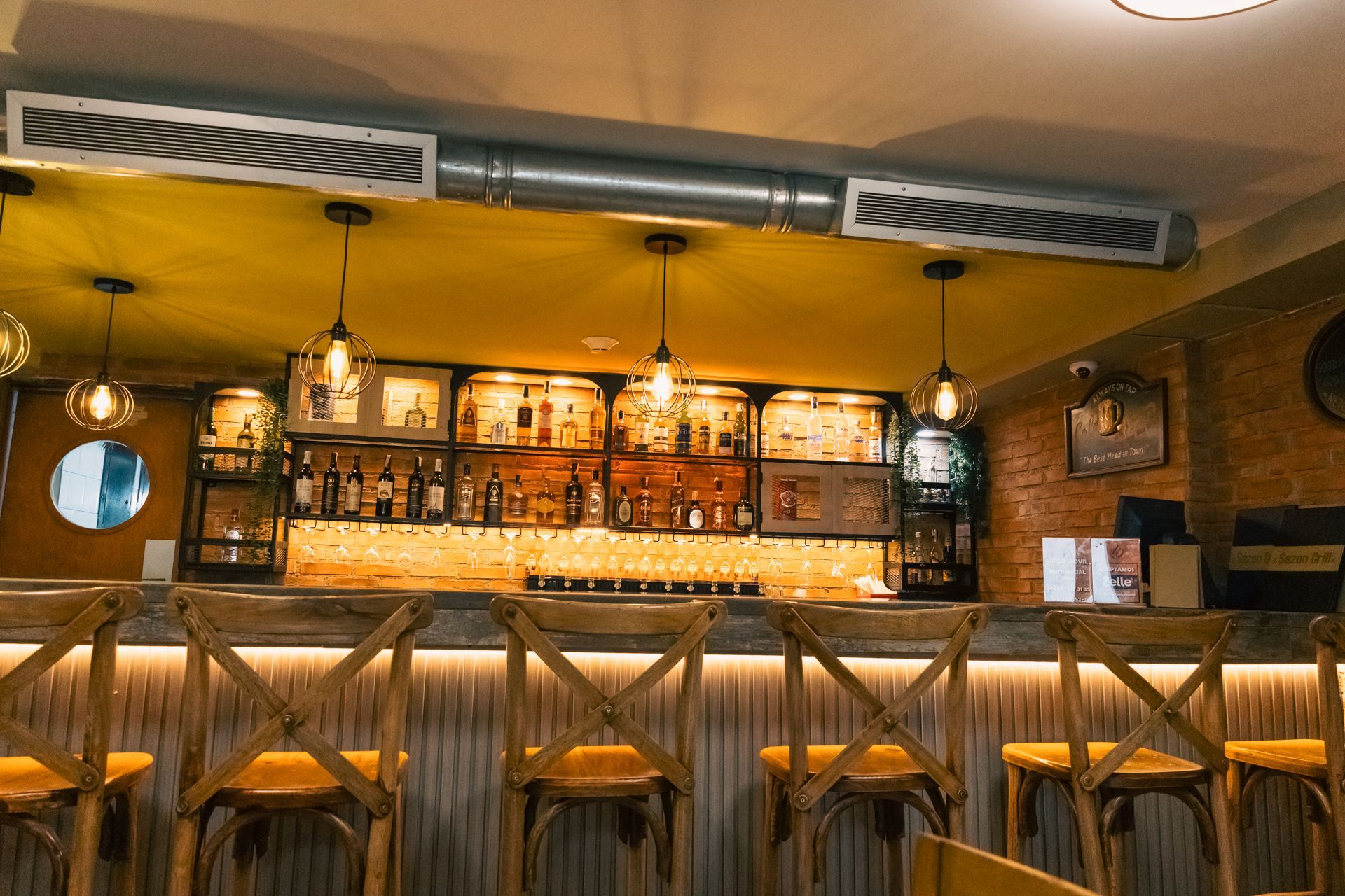 A restaurant with a bar and stools and a brick wall.