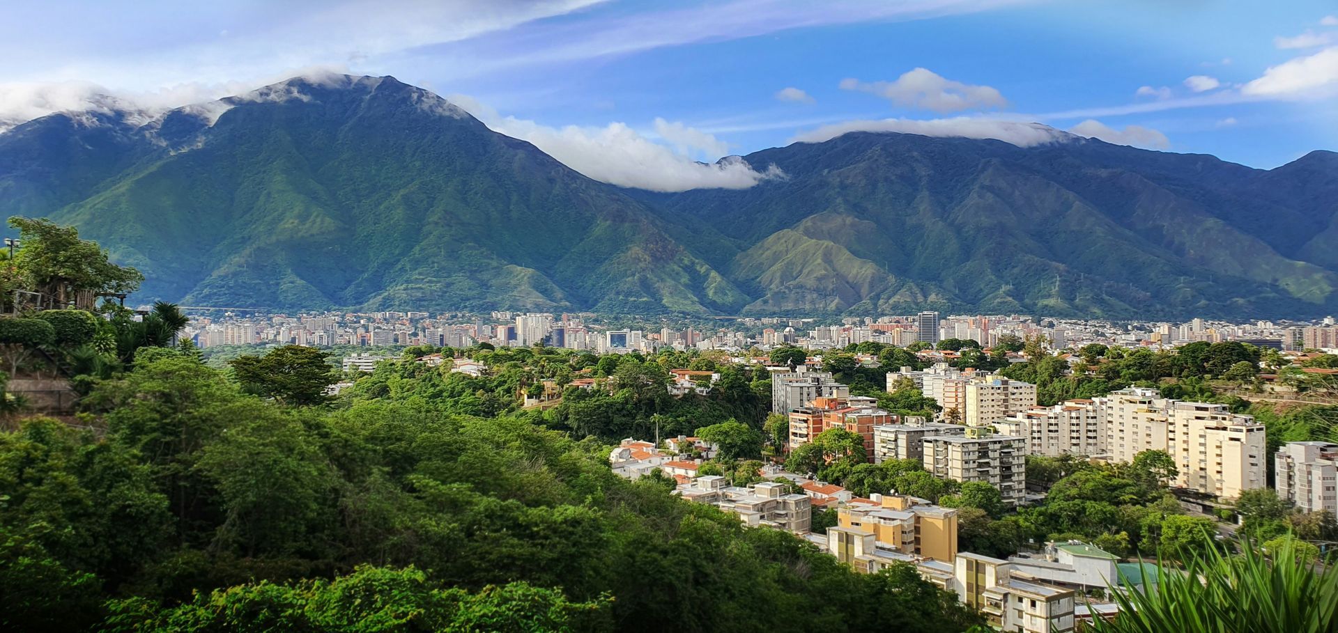 A city surrounded by mountains and trees with a mountain in the background.