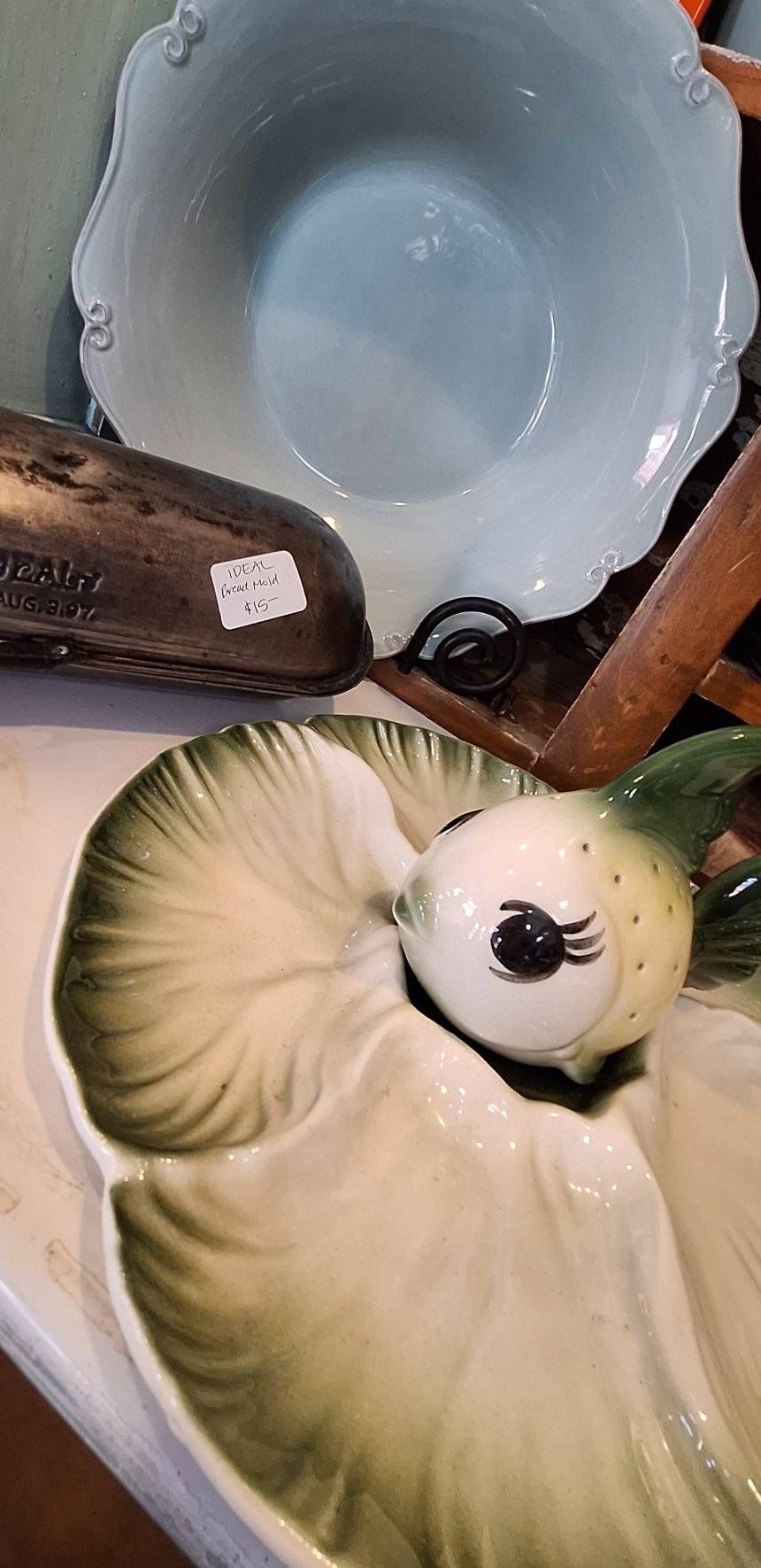 Ceramic fish-shaped dish with a blue bowl and wooden chair in the background.