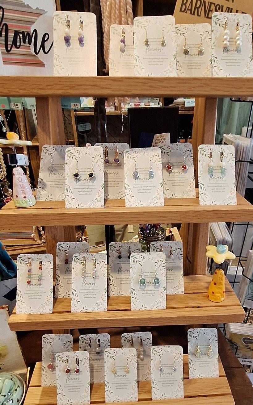 Earrings displayed on a wooden shelf in a store, various styles and colors visible.