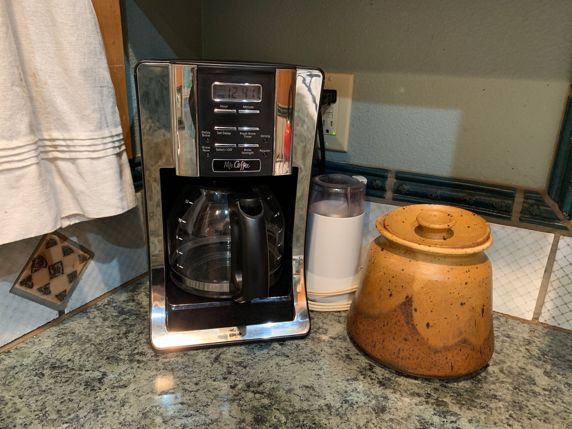 A coffee maker is sitting on a counter next to a jar.