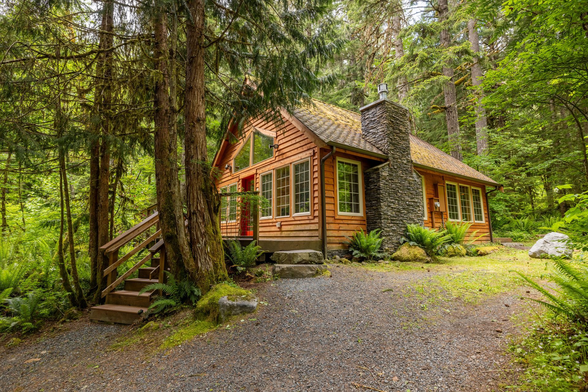 A wooden house with a deck in the middle of the woods