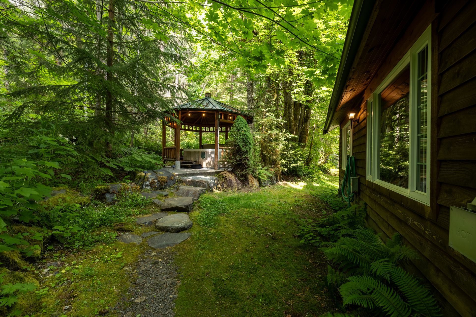 A wooden gazebo with a hot tub inside of it.