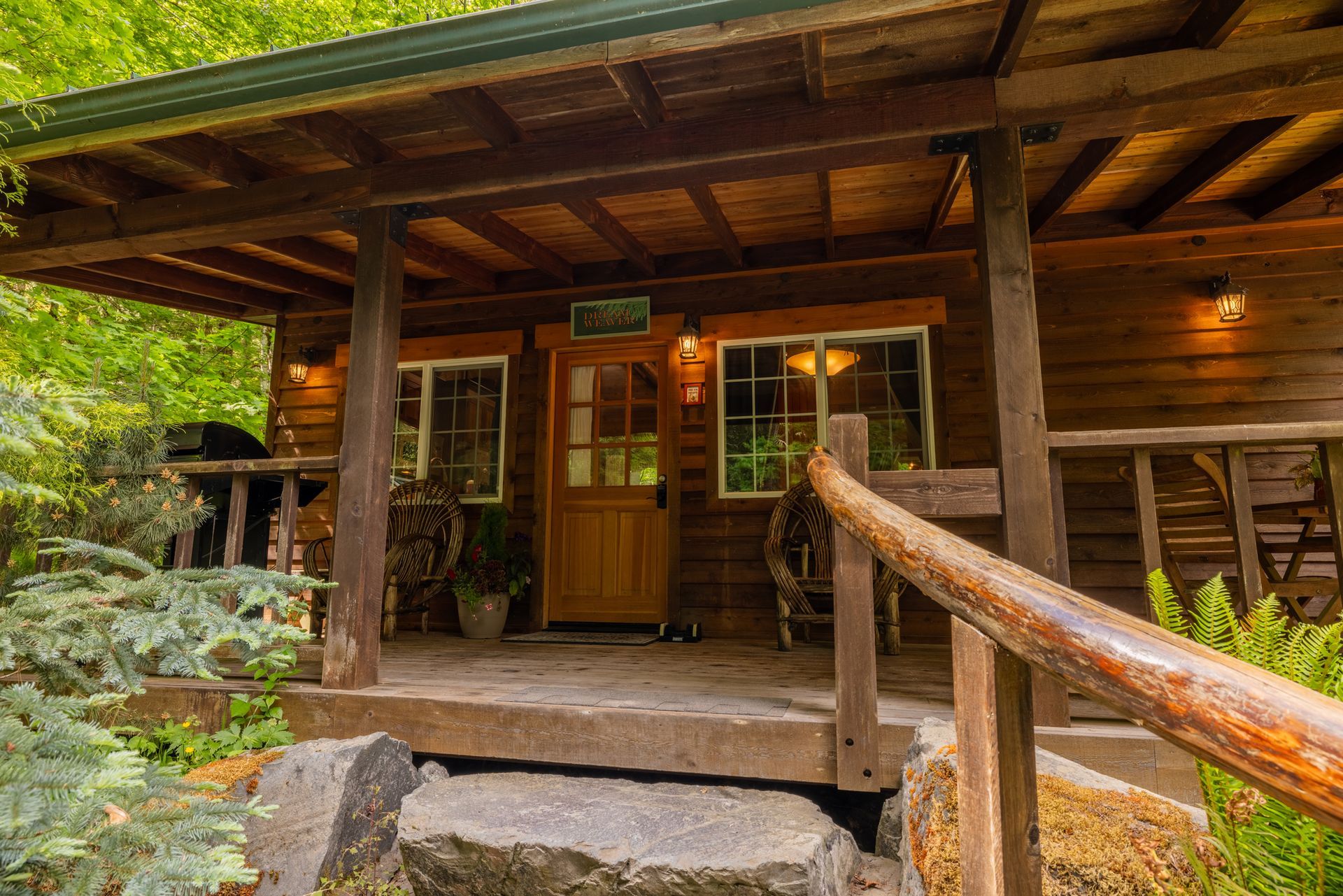 A small wooden cabin in the middle of a forest with stairs leading up to it.