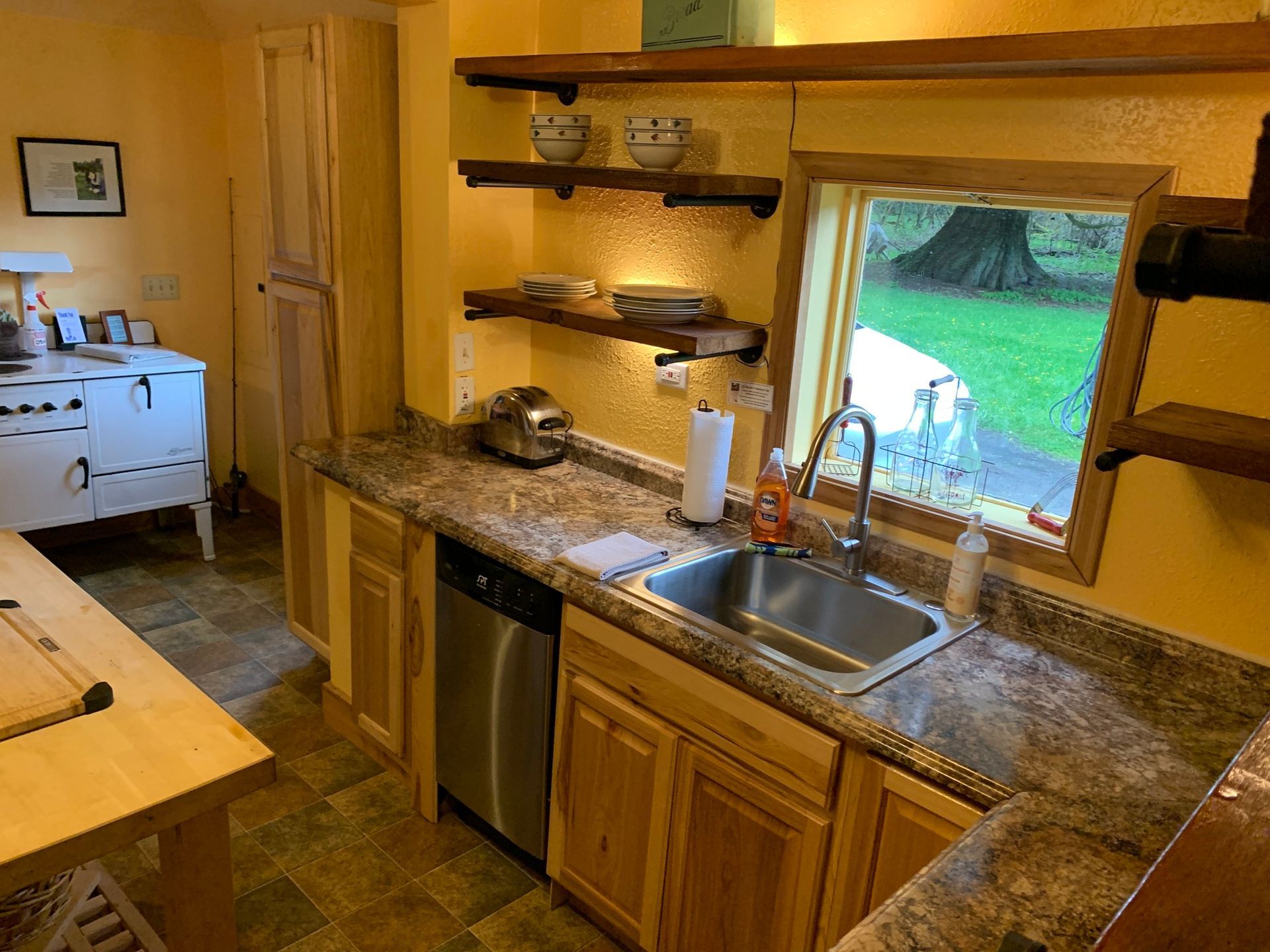 A kitchen with a sink , dishwasher , and stove.