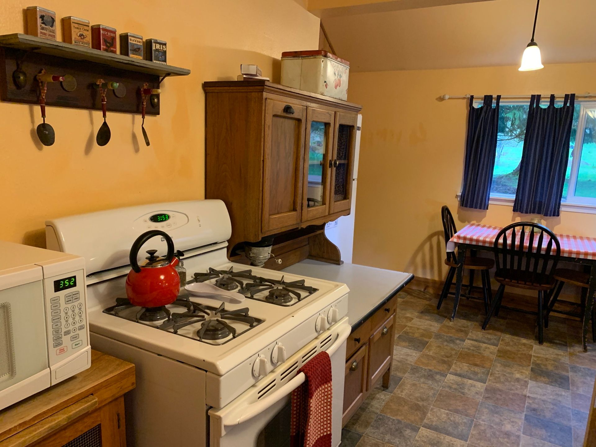 A kitchen with a stove , microwave , table and chairs.