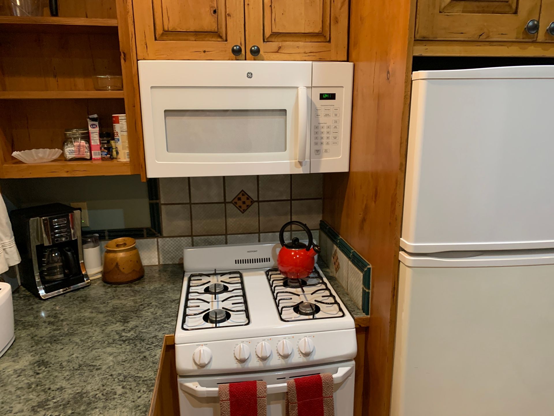 A kitchen with a stove a microwave and a refrigerator