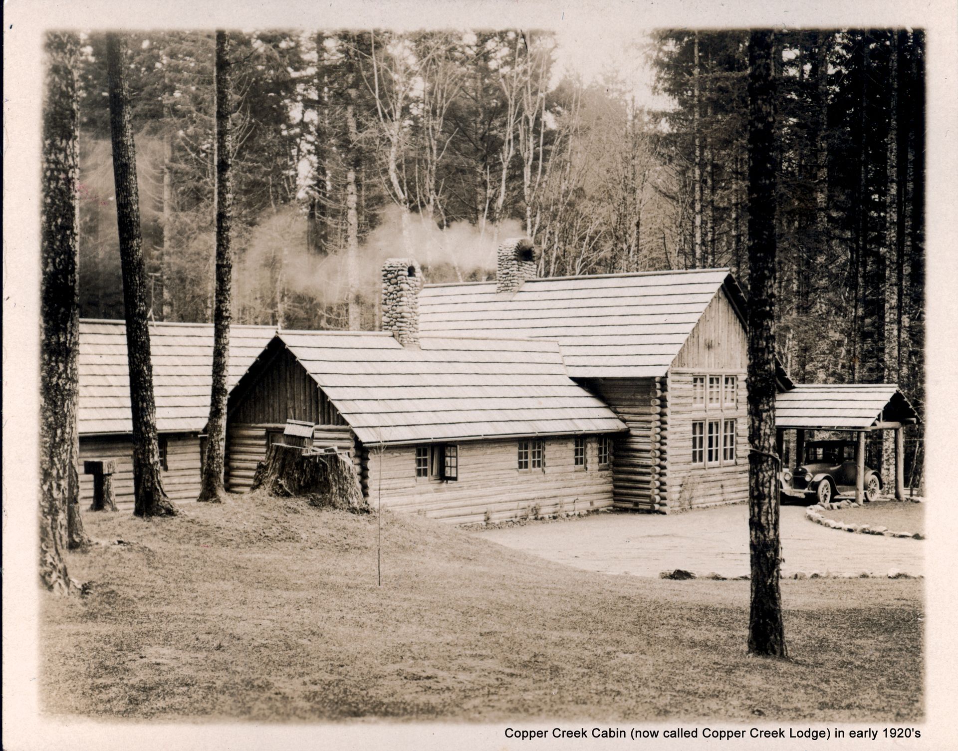 A black and white photo of a log cabin in the woods