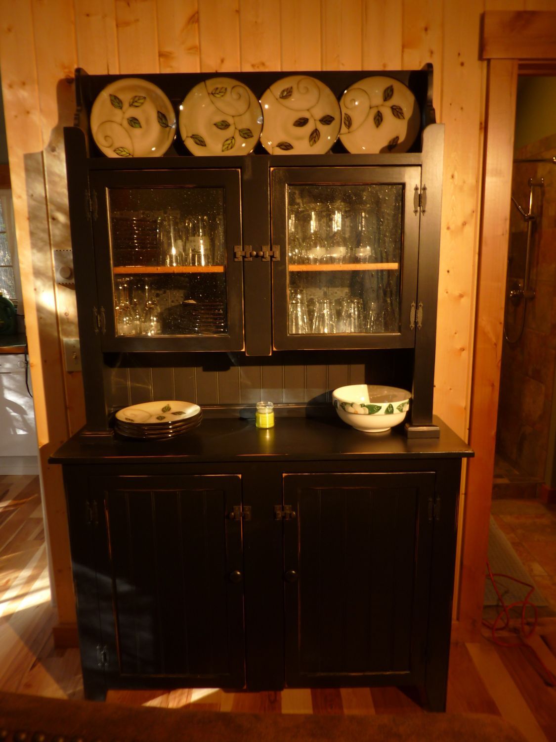A black cabinet with plates and glasses on it