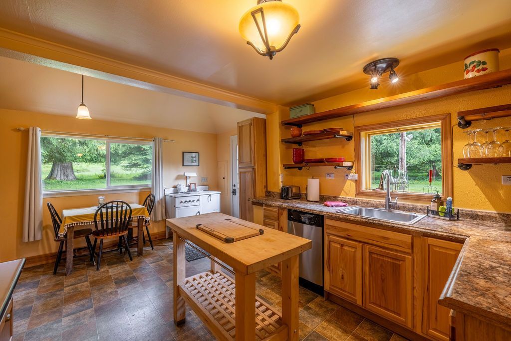 A kitchen with a wooden island and countertops. A window looks out onto a grassy field. Warm yellow walls and cabinets.