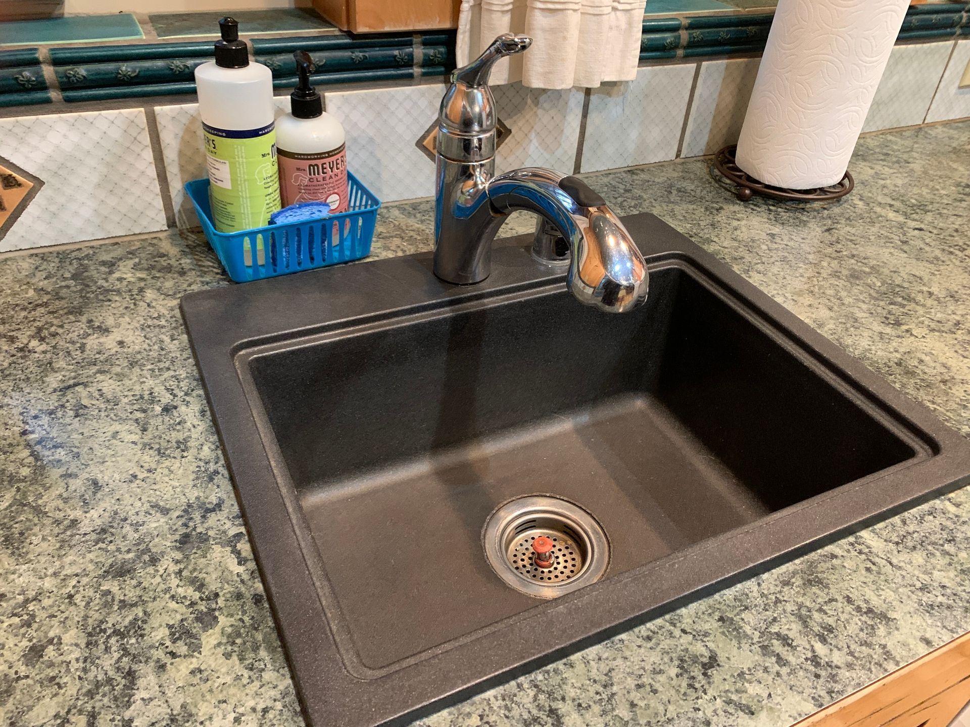 A kitchen sink with a faucet and soap dispensers on the counter.