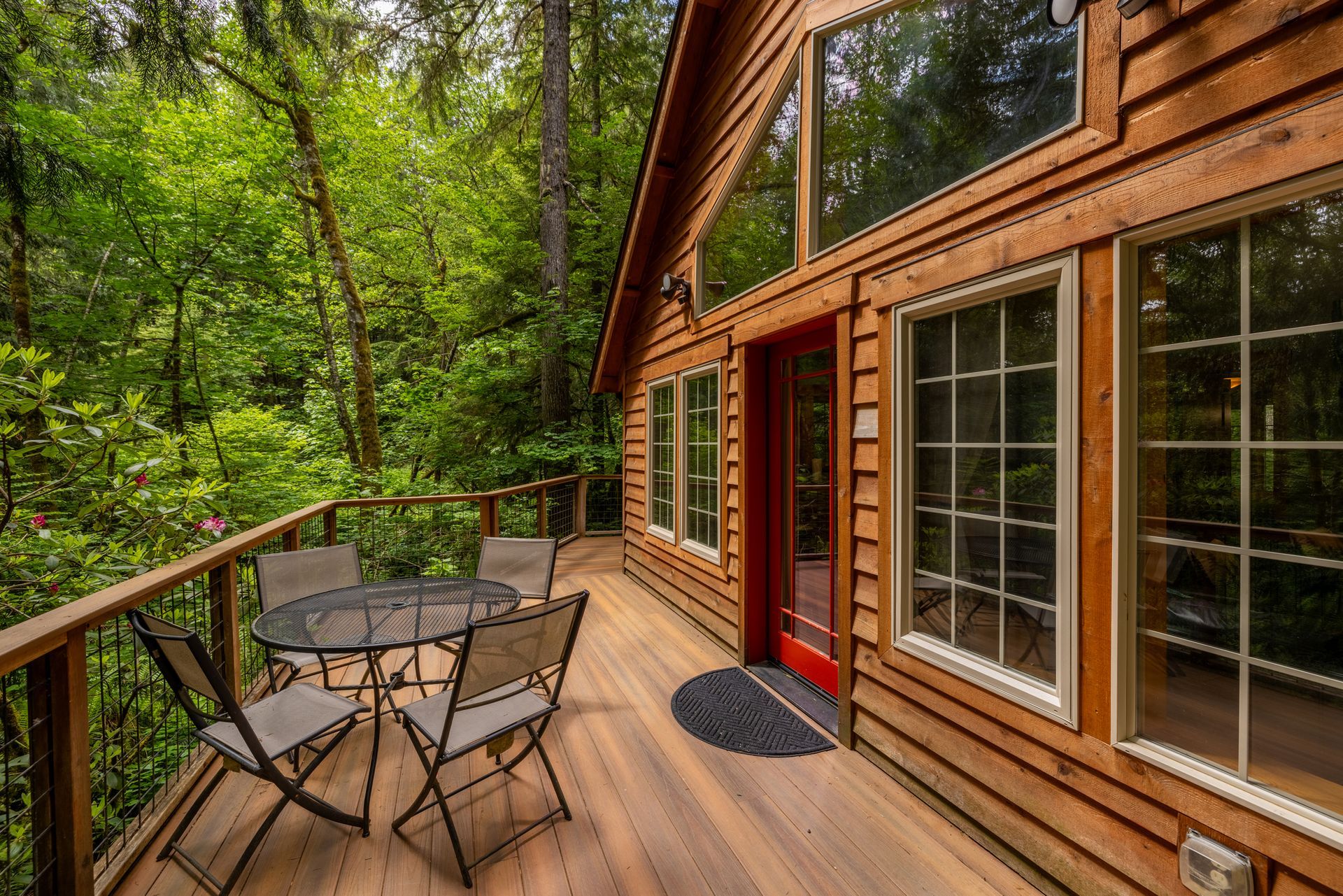 A wooden house with a deck in the middle of the woods