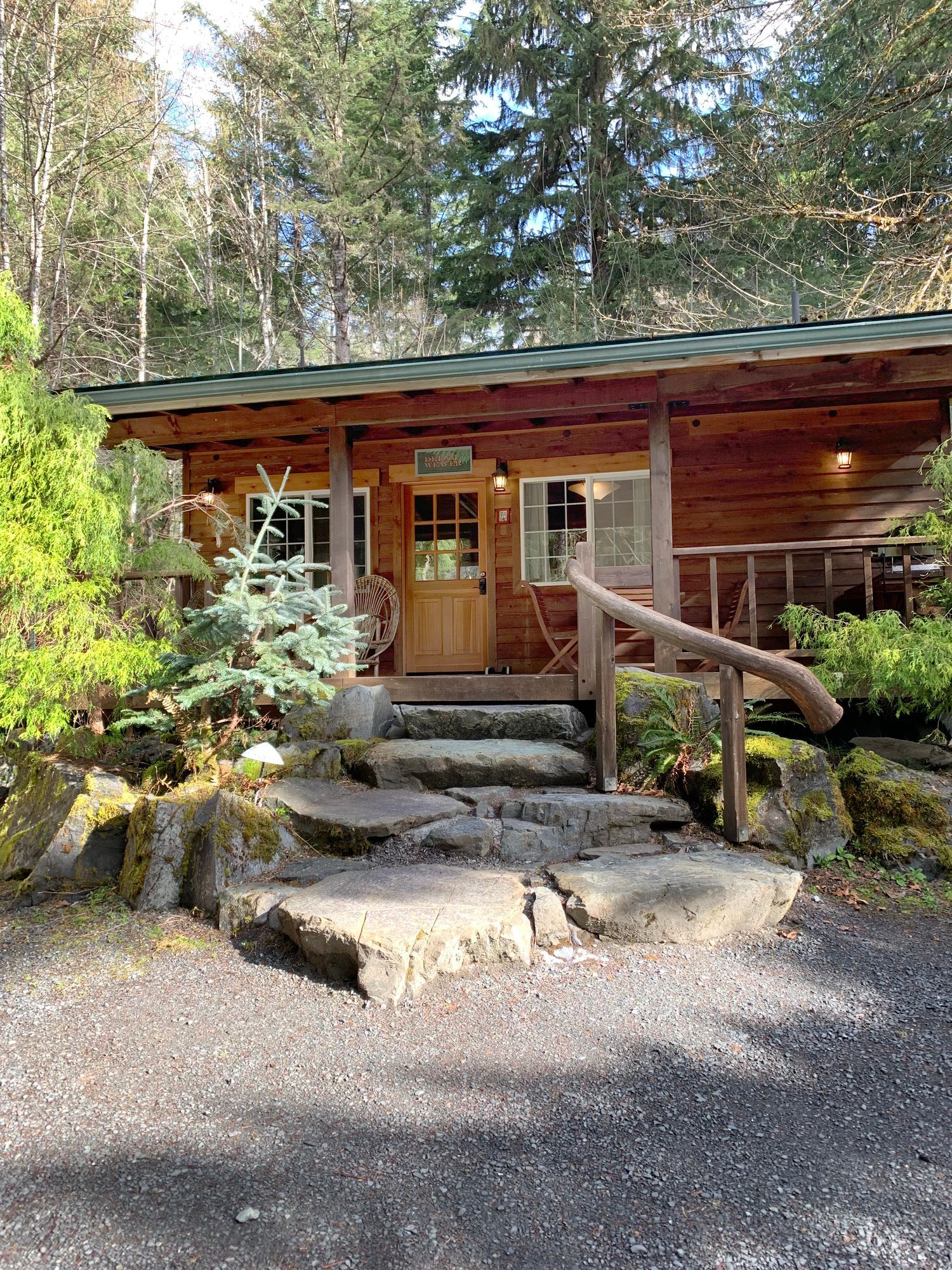 A small wooden cabin in the middle of a forest with stairs leading up to it.