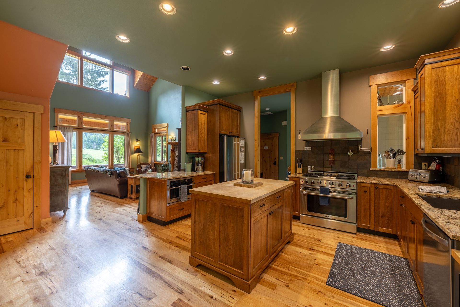 Spacious kitchen with wood cabinets, granite countertops, and stainless steel appliances. Features two islands and a view into a living room.