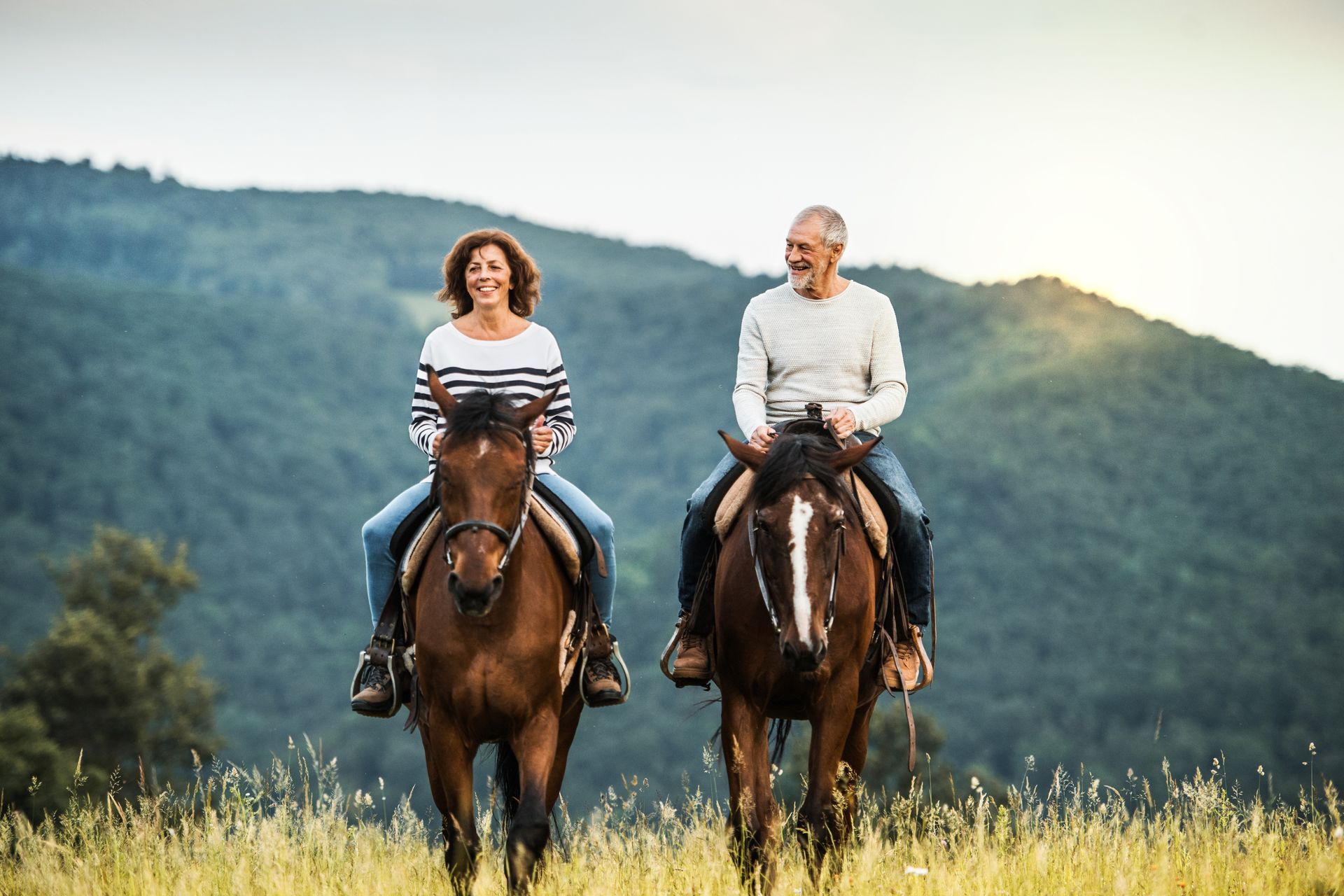 A man and a woman are riding horses in a field.