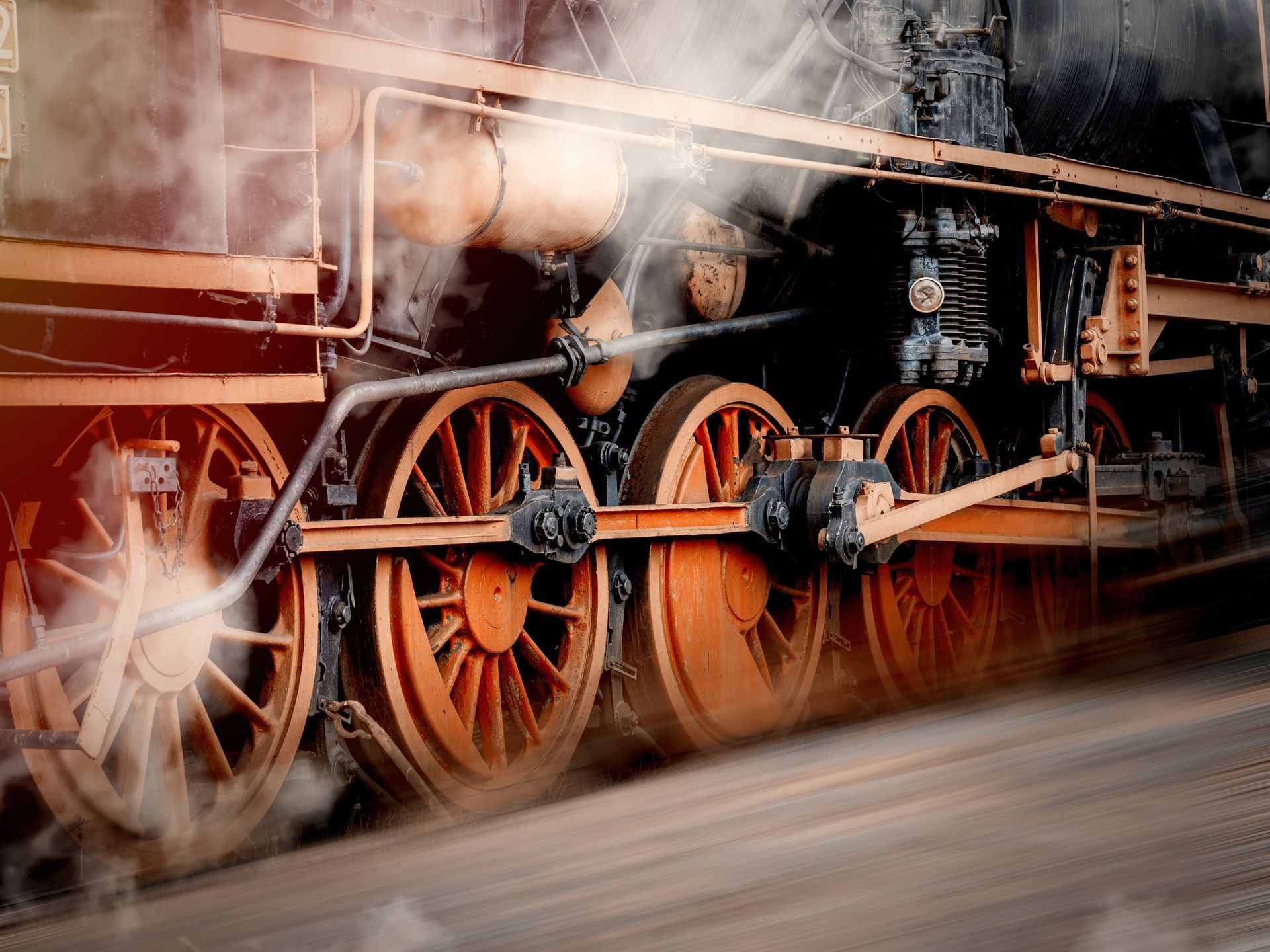 A close up of the wheels of a train with smoke coming out of them.