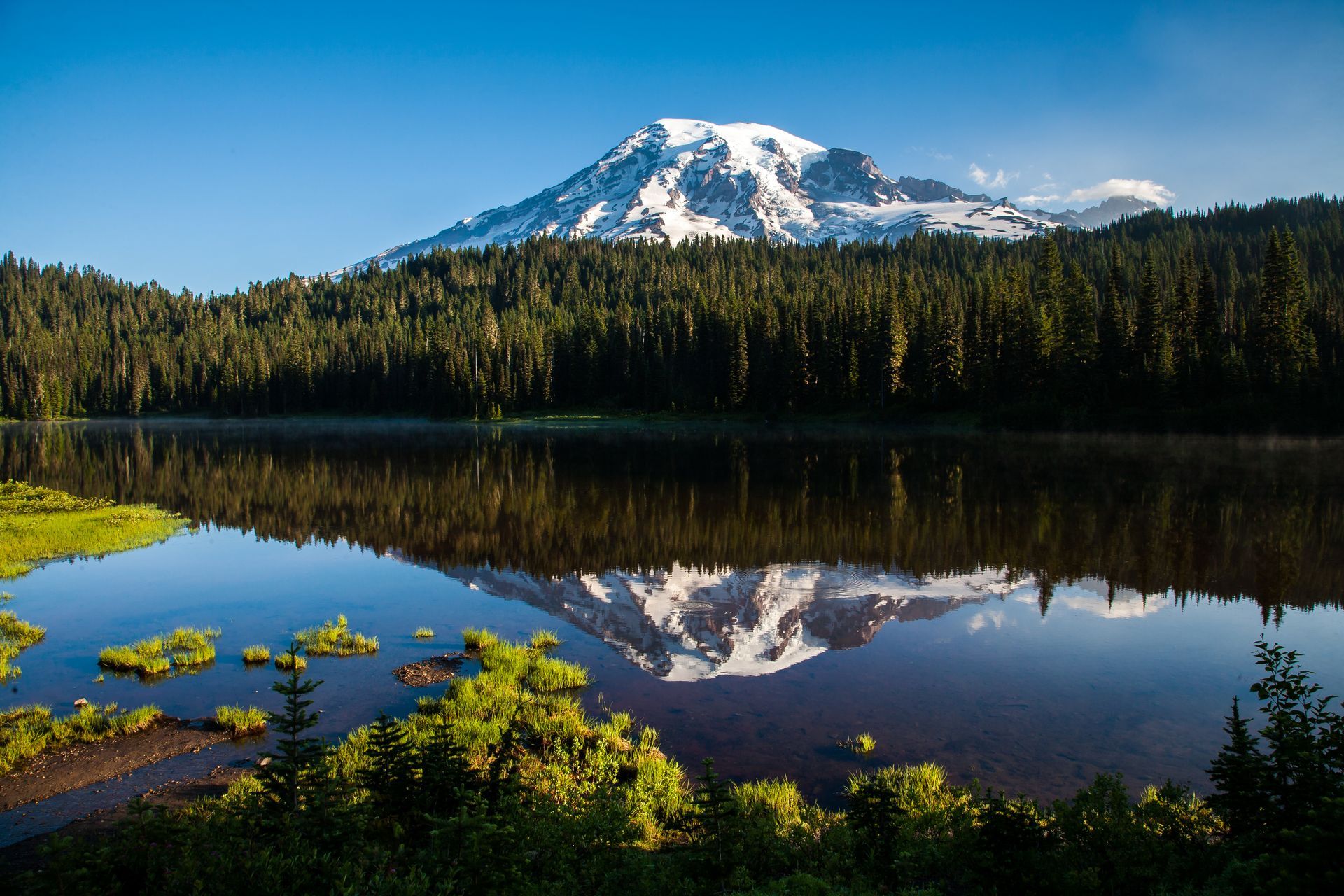 A mountain is reflected in a lake surrounded by trees