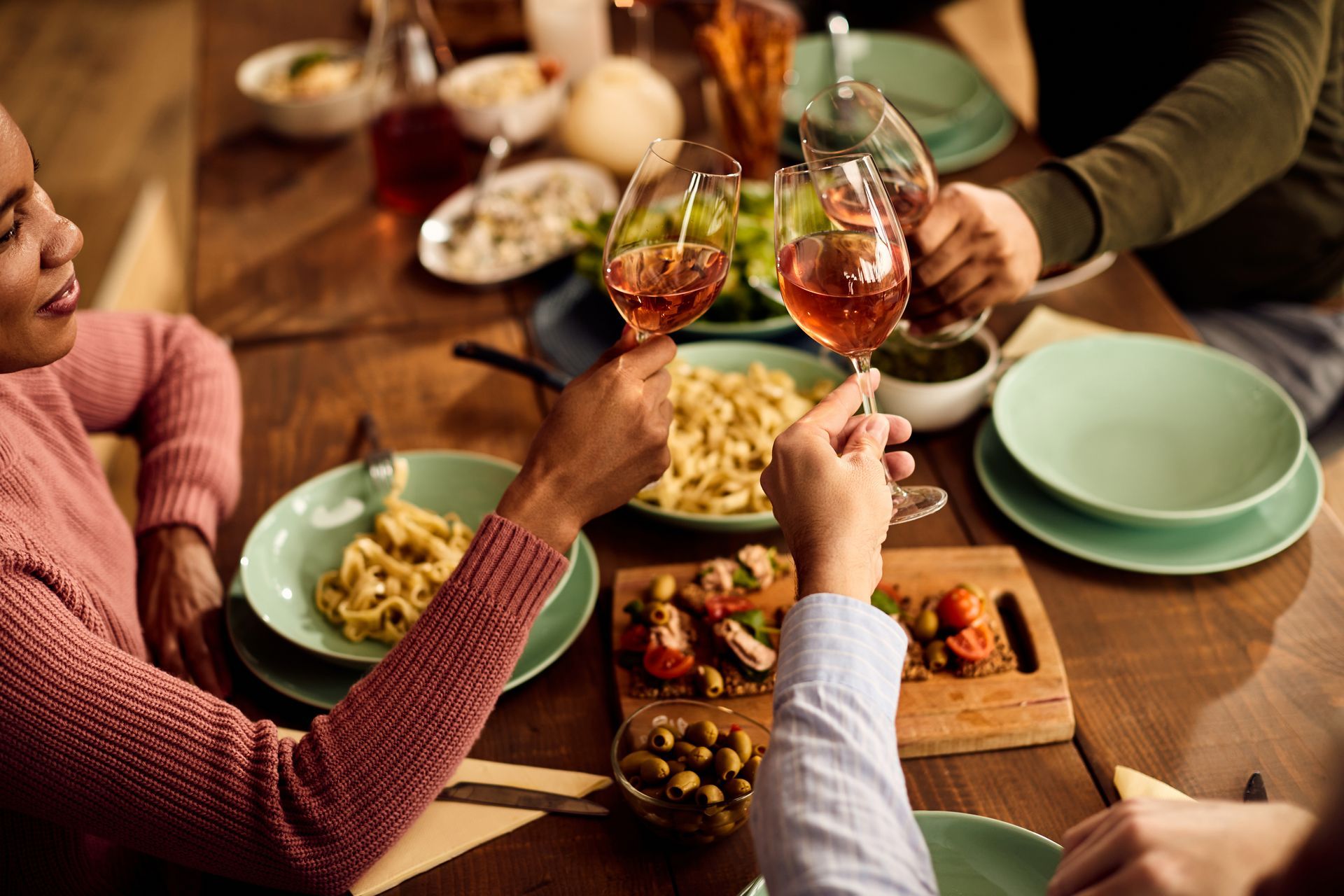 A group of people are sitting at a table eating food and drinking wine.