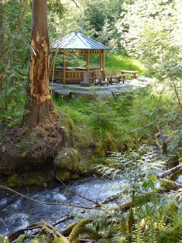 A gazebo in the middle of a forest next to a river.