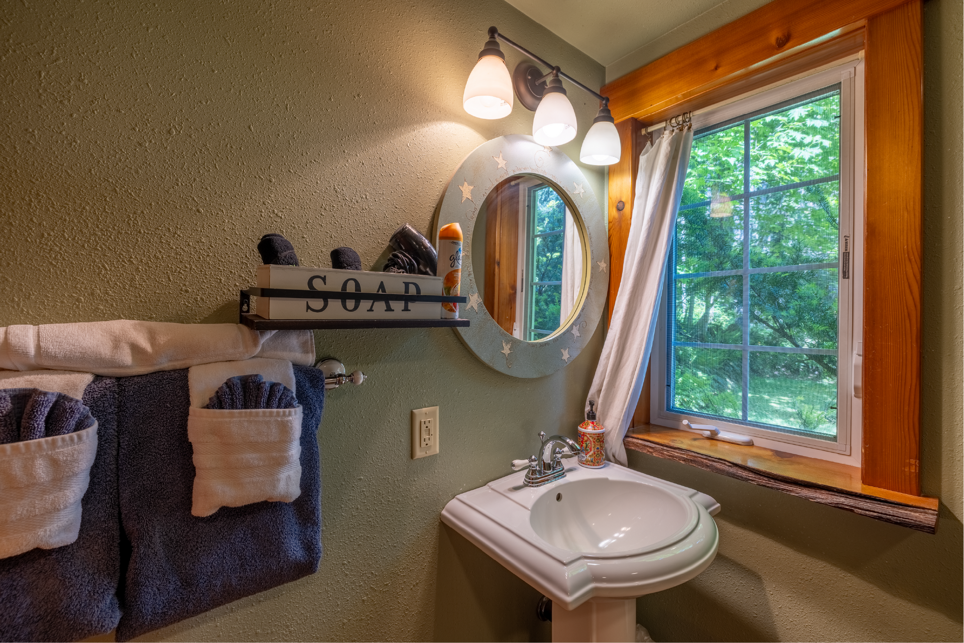 A bathroom with a sink , mirror , and soap box.