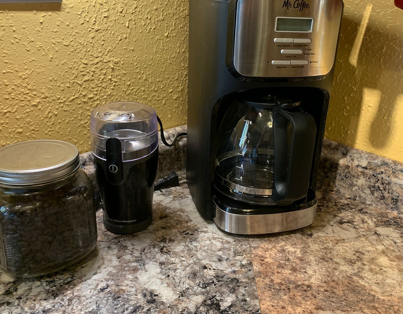 A coffee maker is sitting on a counter next to a jar of coffee beans.
