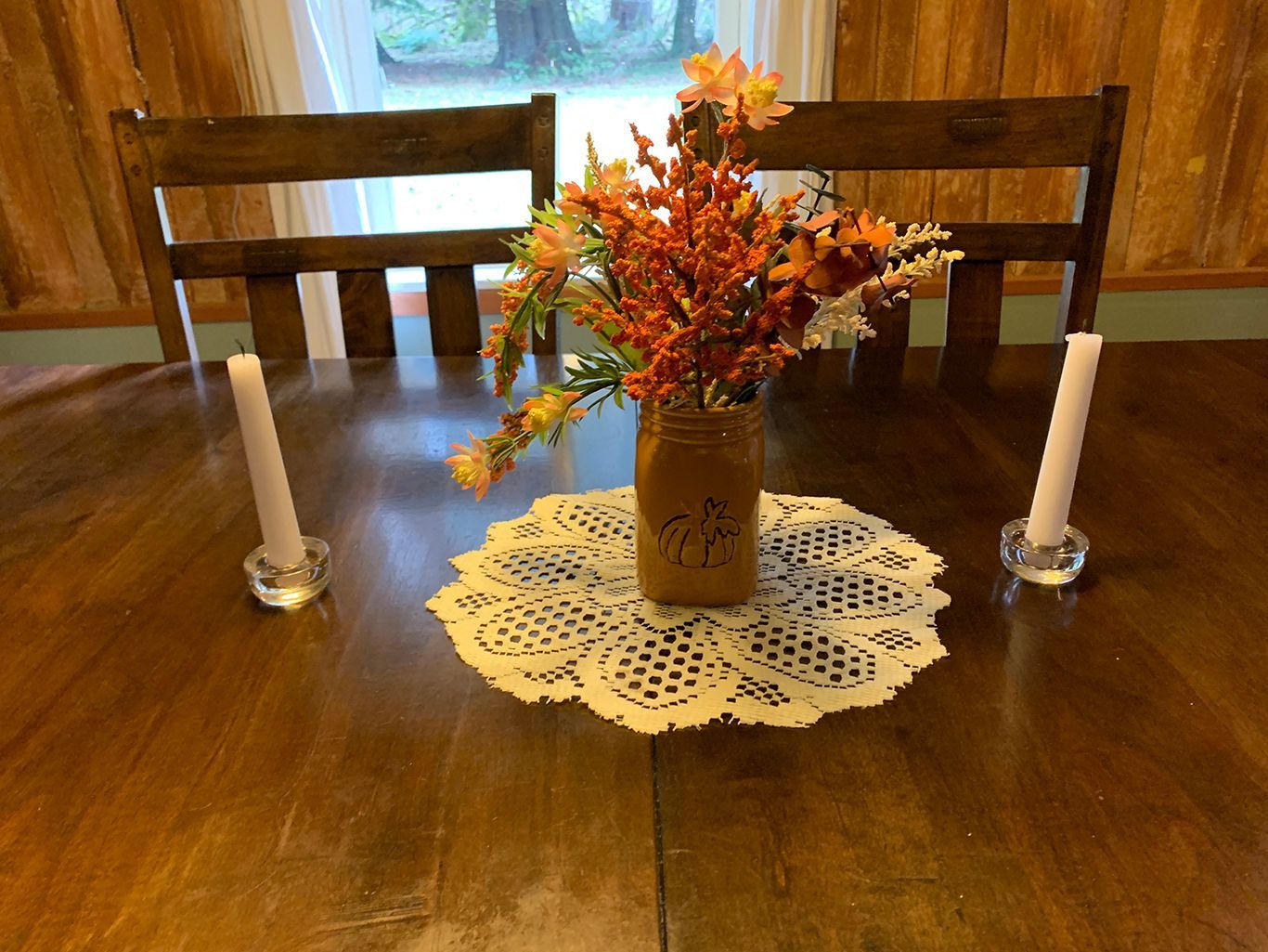 A table with a vase of flowers and two candles on it