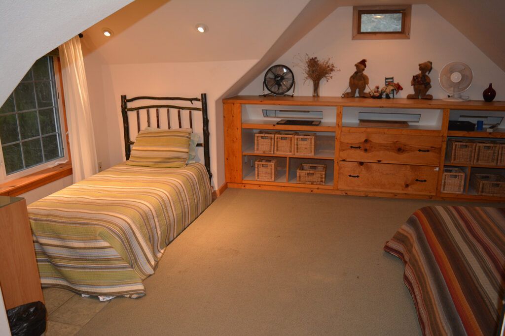 A bedroom with two beds and a fan on the wall