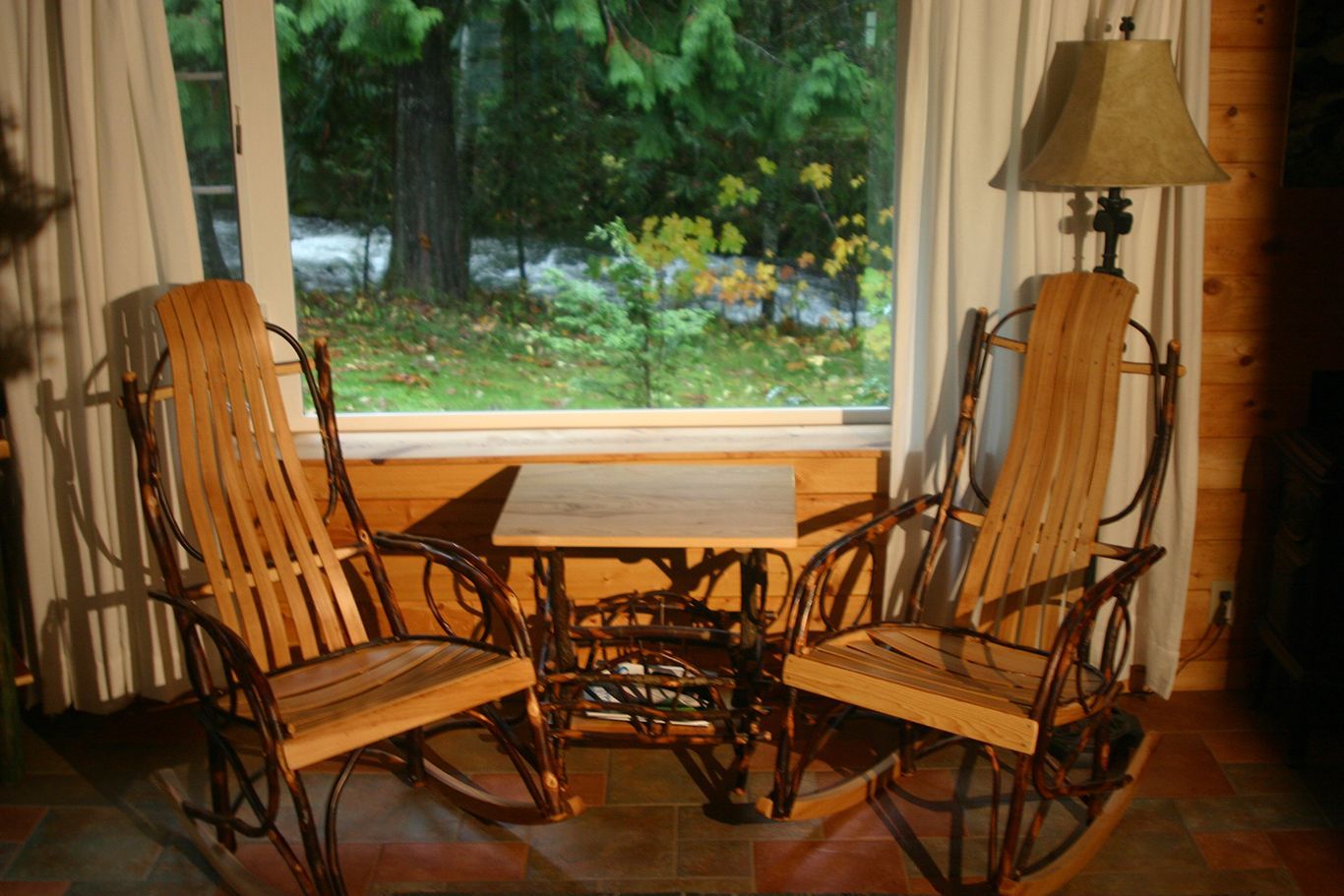 Two rocking chairs and a table in front of a window