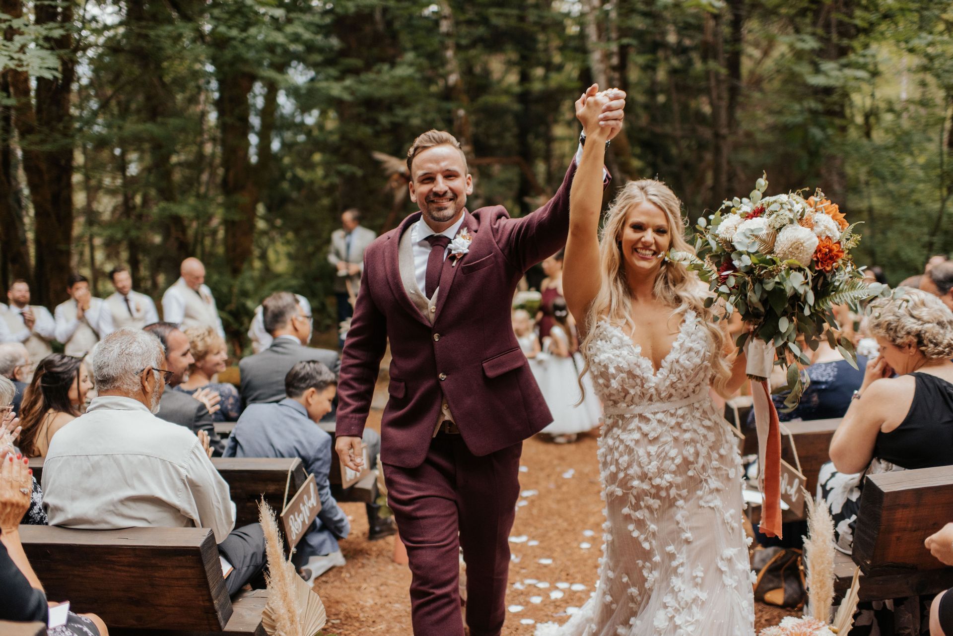 A bride and groom are walking down the aisle holding hands.