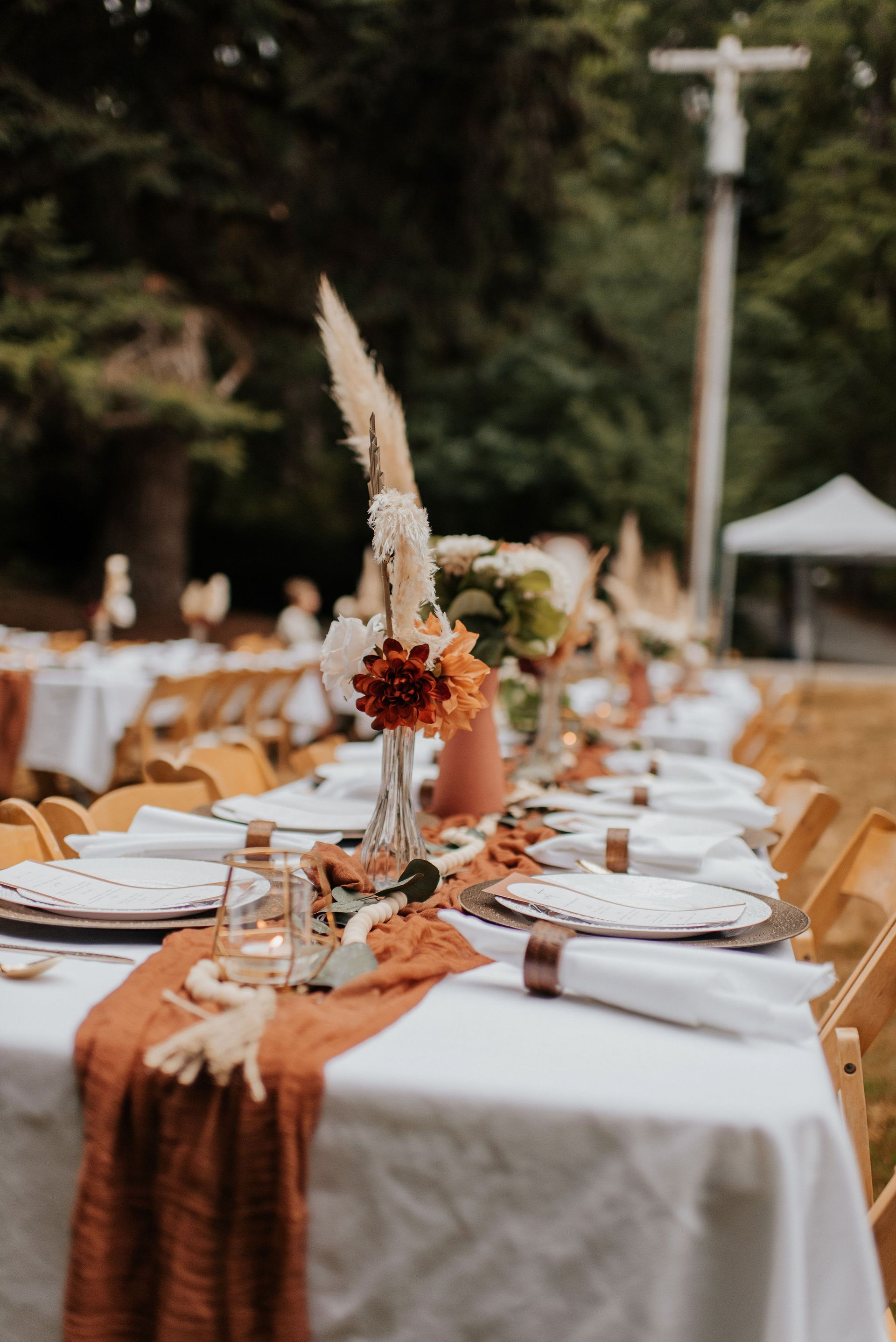 A long table set for a wedding reception with plates , napkins , candles and flowers.