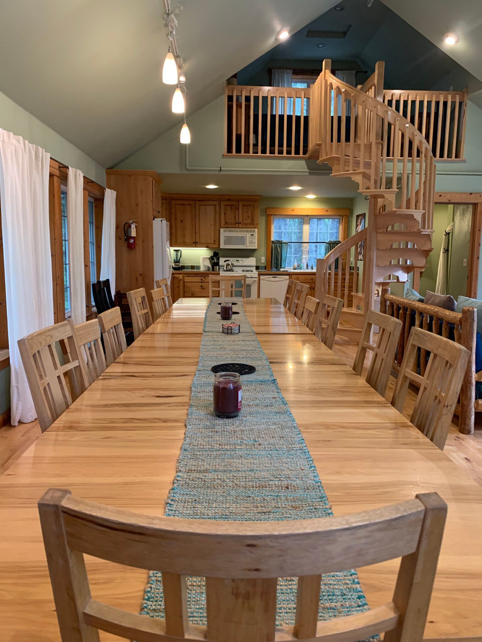 A long wooden table and chairs in a large room with a spiral staircase.