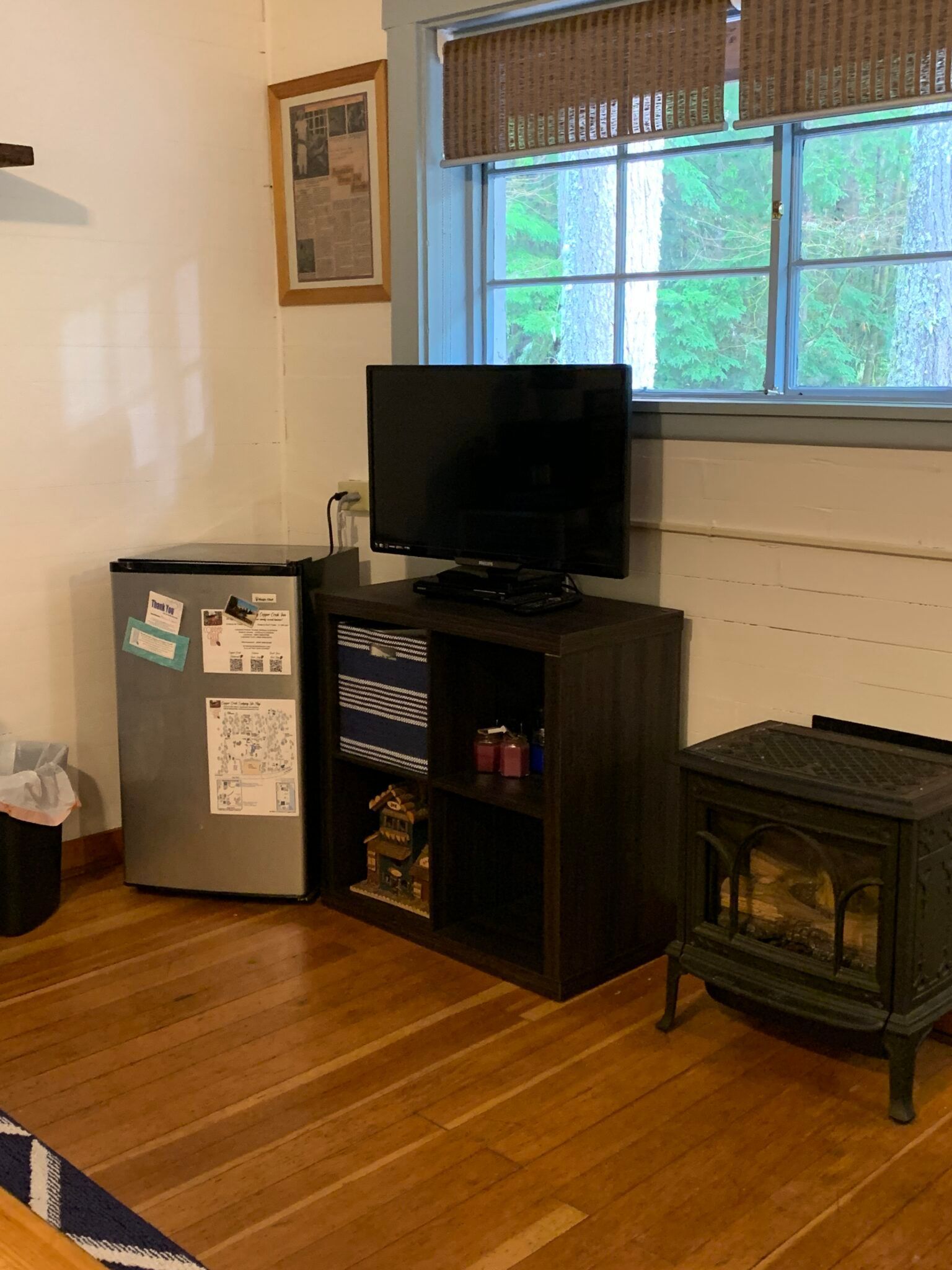 A living room with a television , stove and refrigerator.