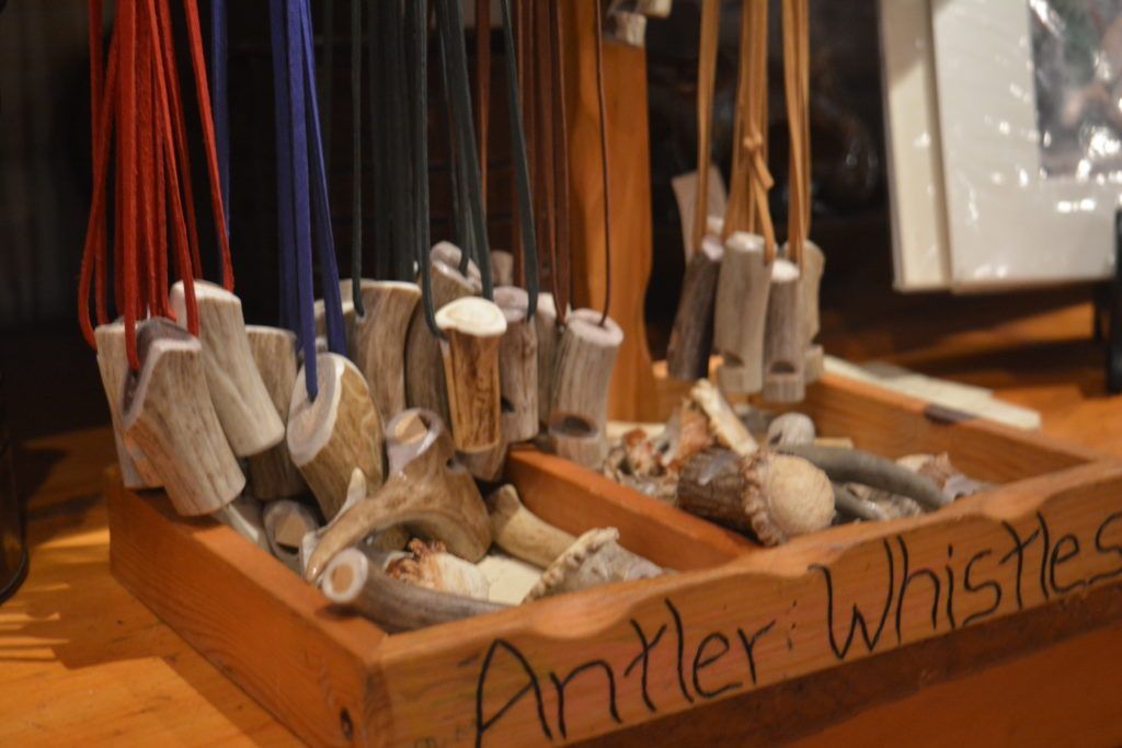 A wooden box filled with antler whistles on a table.