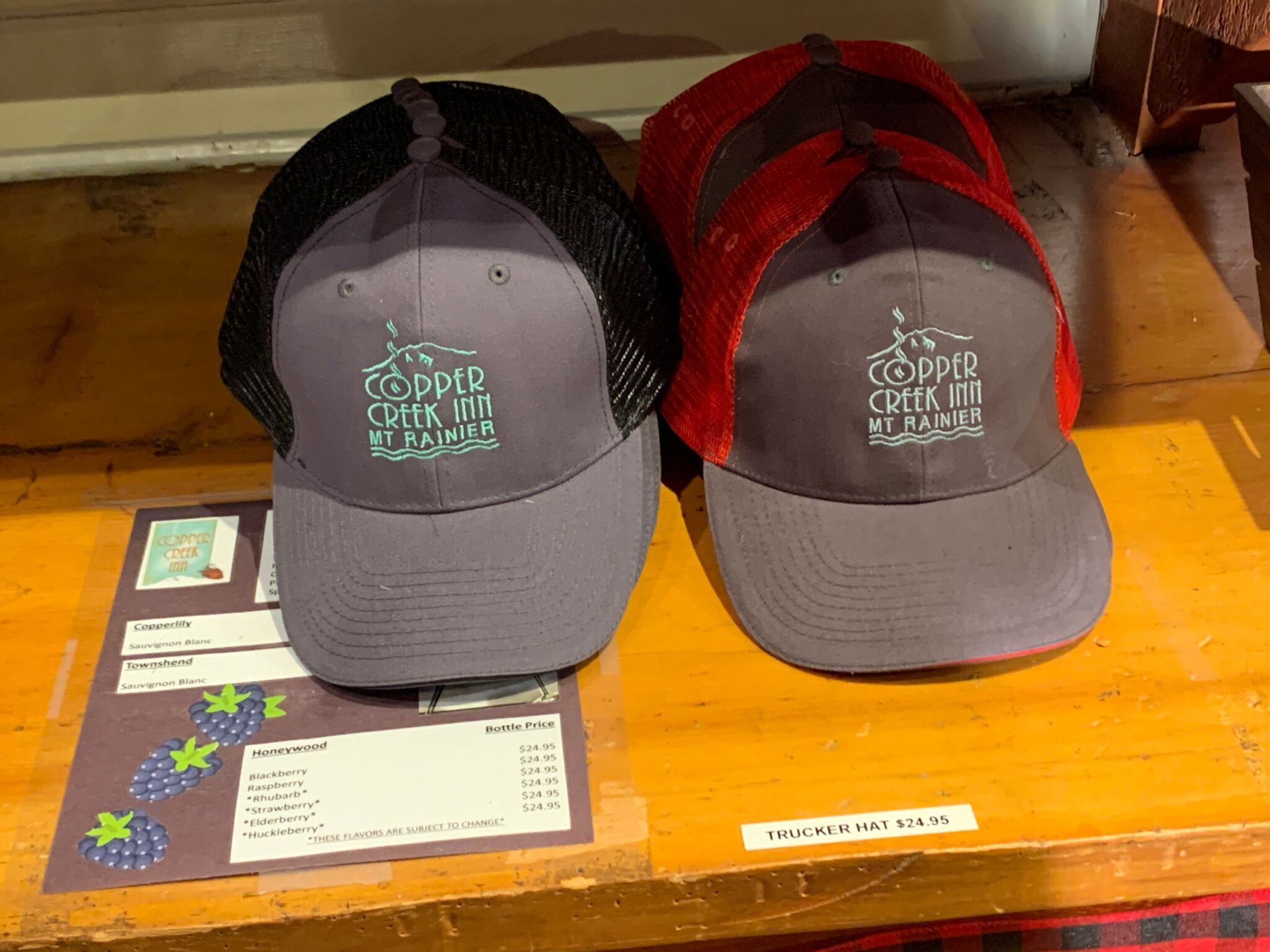 Two hats are sitting on a wooden shelf and one of them says camp creek in florida