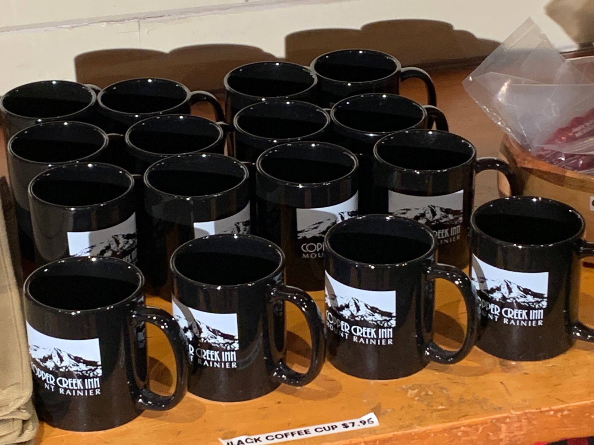 A bunch of black coffee mugs with mountains on them