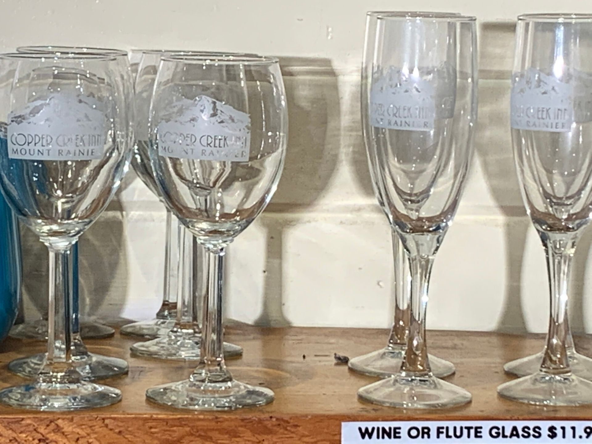 A row of wine glasses are sitting on a wooden table.