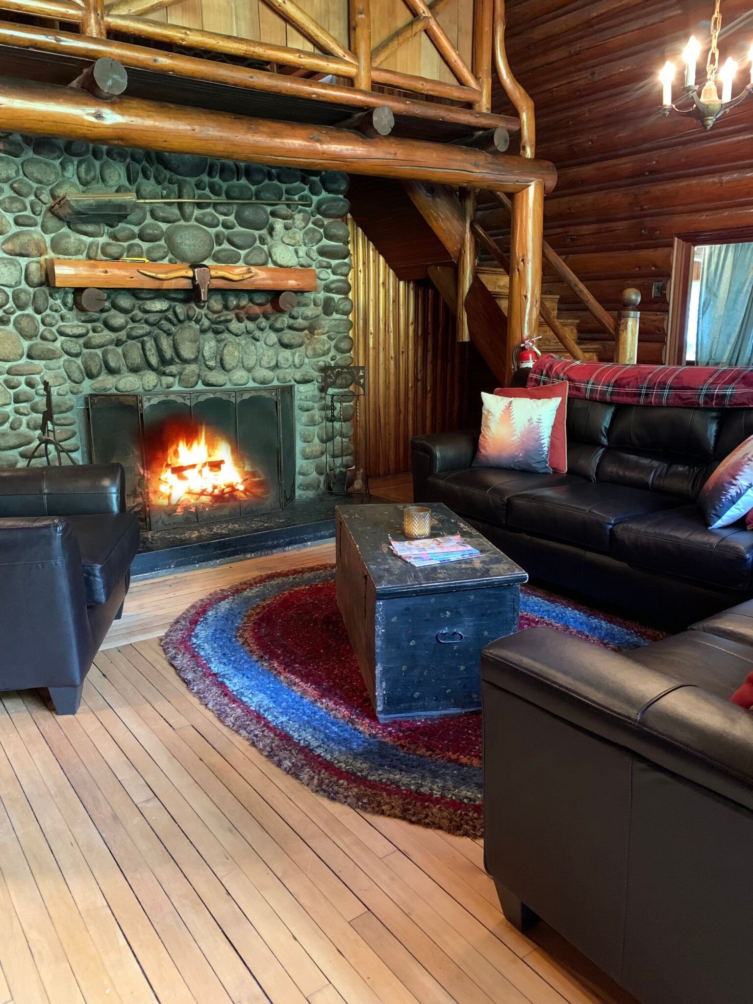 A living room in a log cabin with a fireplace and a couch.