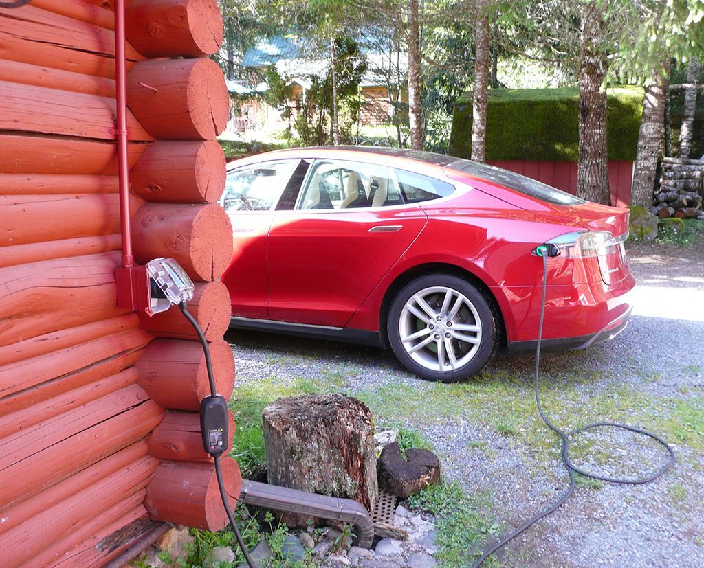 A red car is parked next to a log cabin