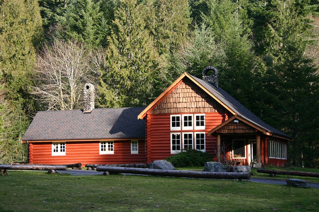 A large red log cabin in the middle of a forest