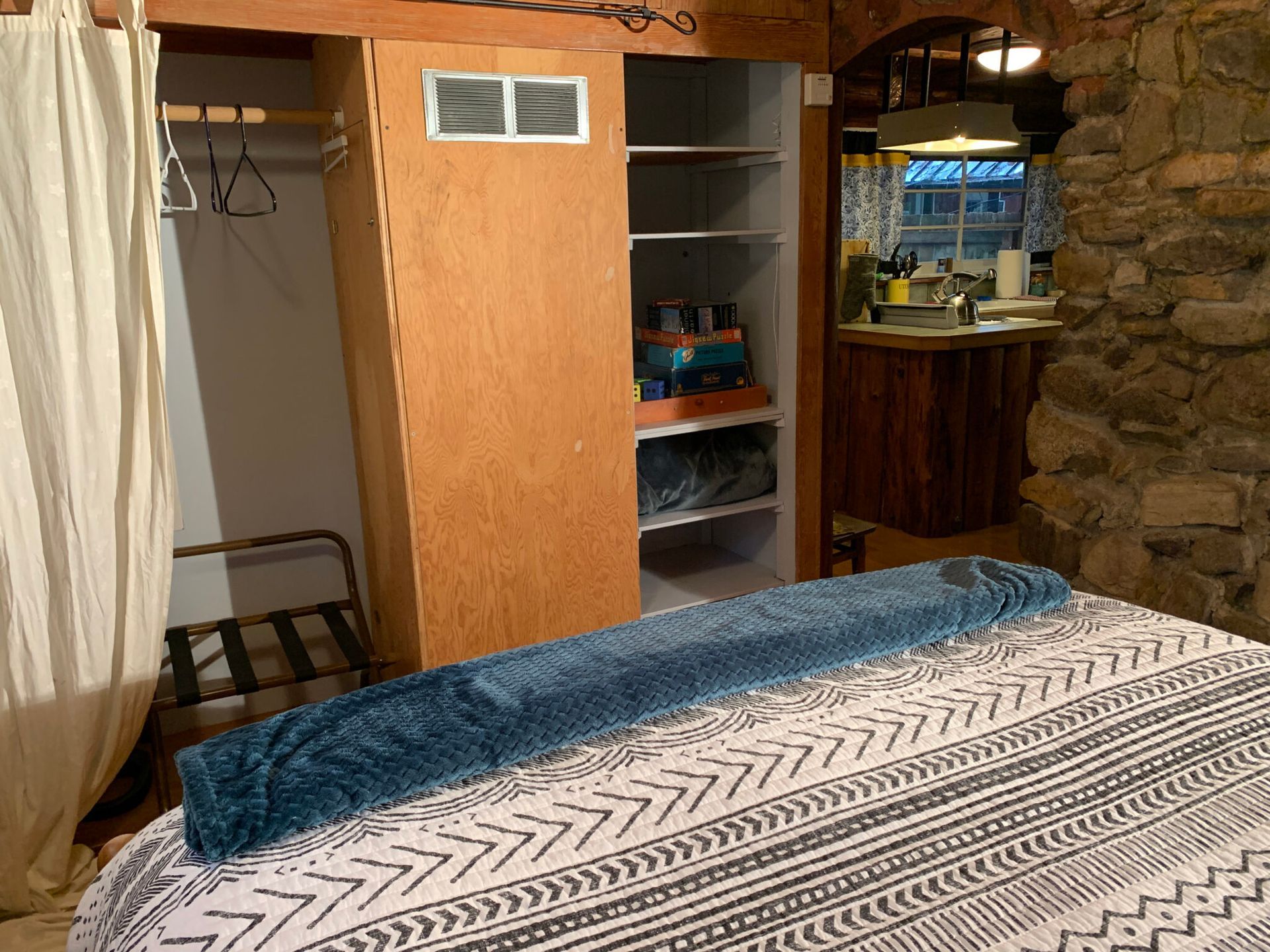 A bedroom with a bed , closet and a stone wall.