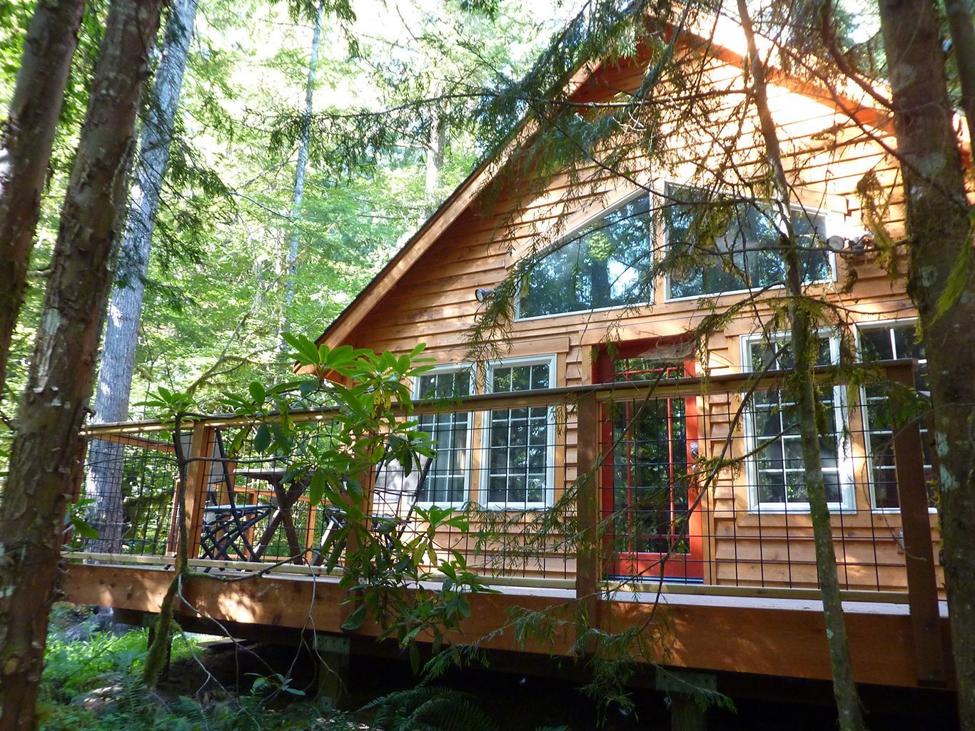 A wooden house with a deck in the middle of the woods