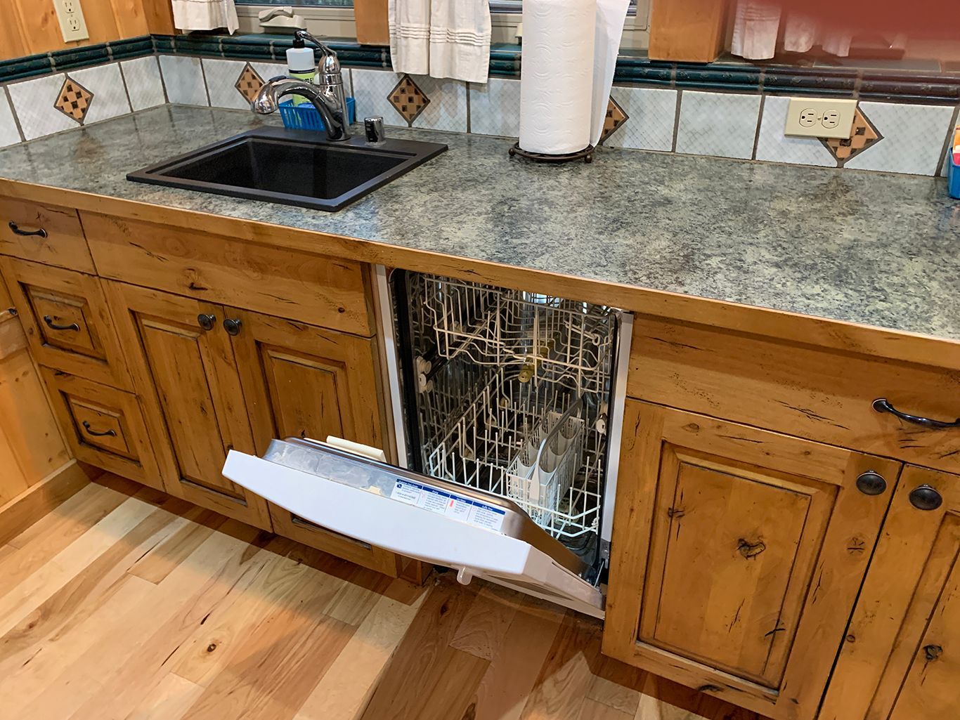 A kitchen with a sink and a dishwasher with the door open.
