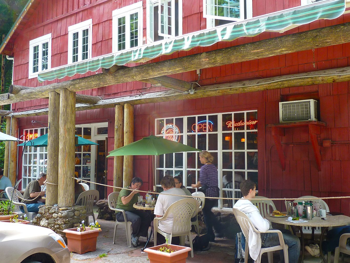 A group of people are sitting at tables outside of a restaurant.