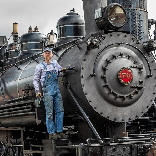 A man is standing on the front of a train with the number 70 on it.