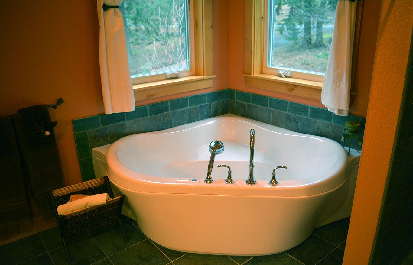 A bathtub in the corner of a bathroom next to a window