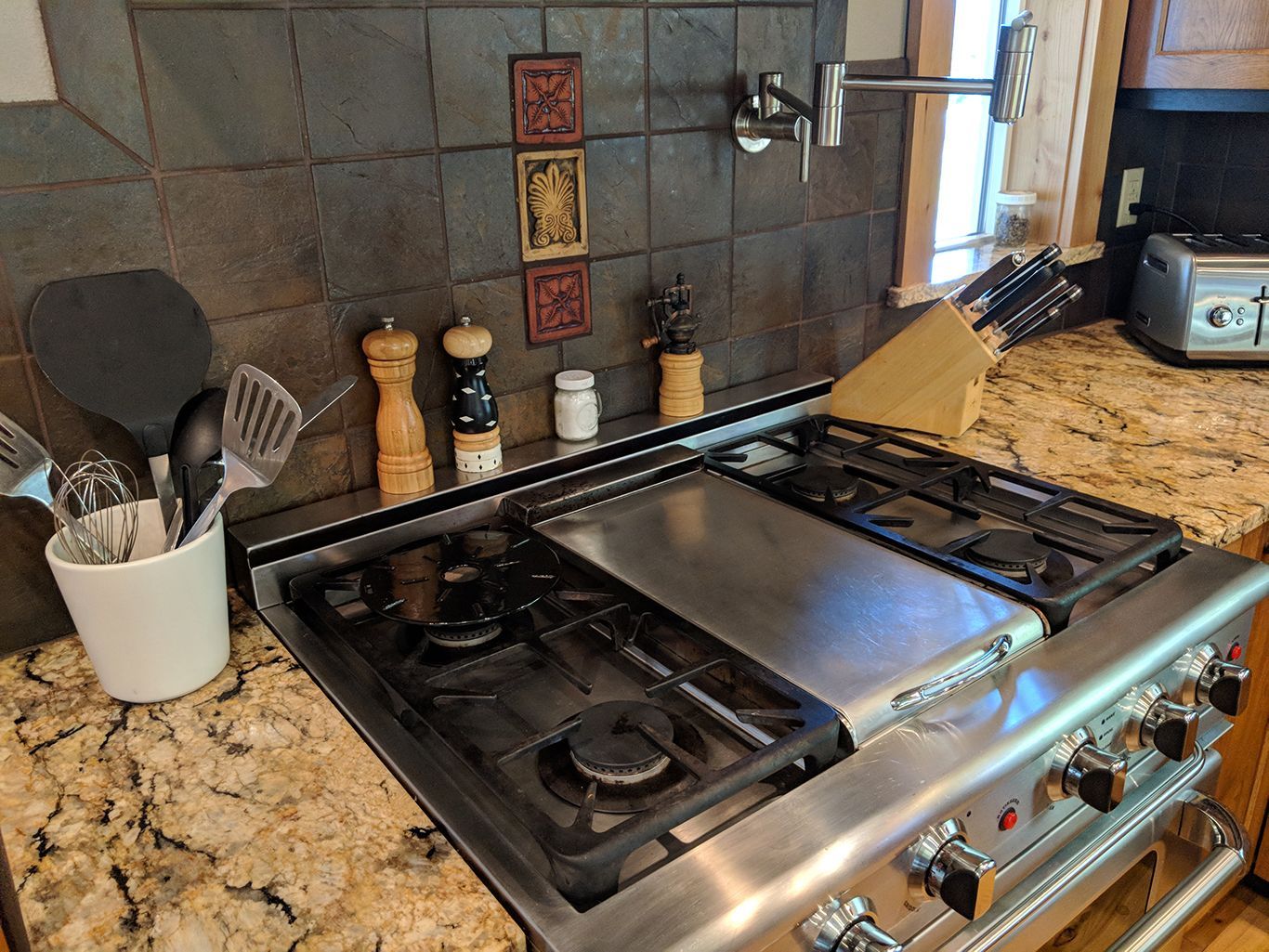 A stove top oven is sitting on top of a granite counter in a kitchen.