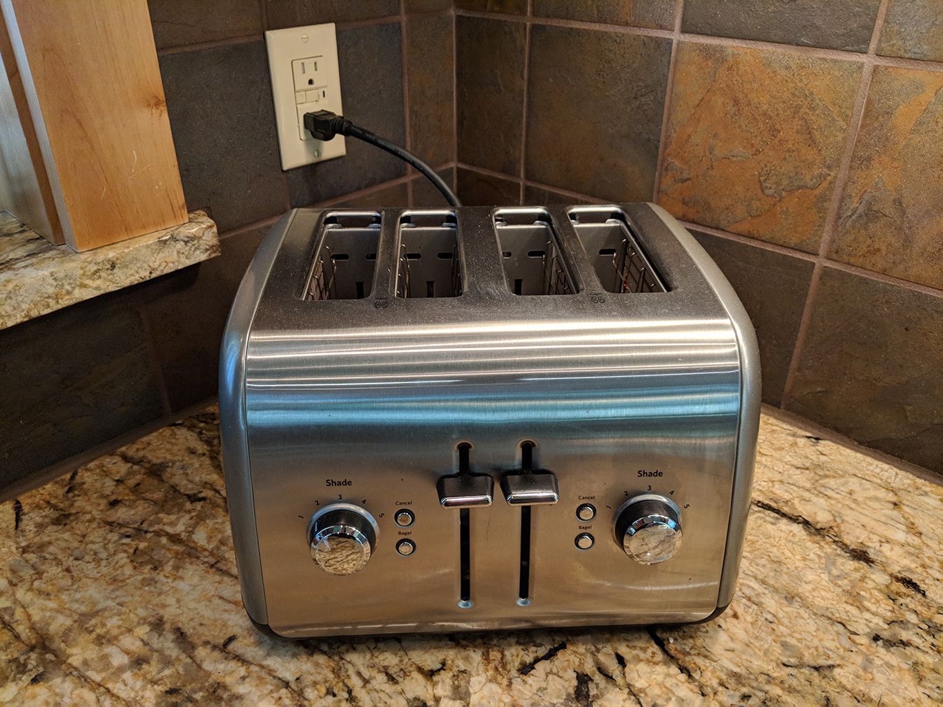 A stainless steel toaster is sitting on a granite counter.