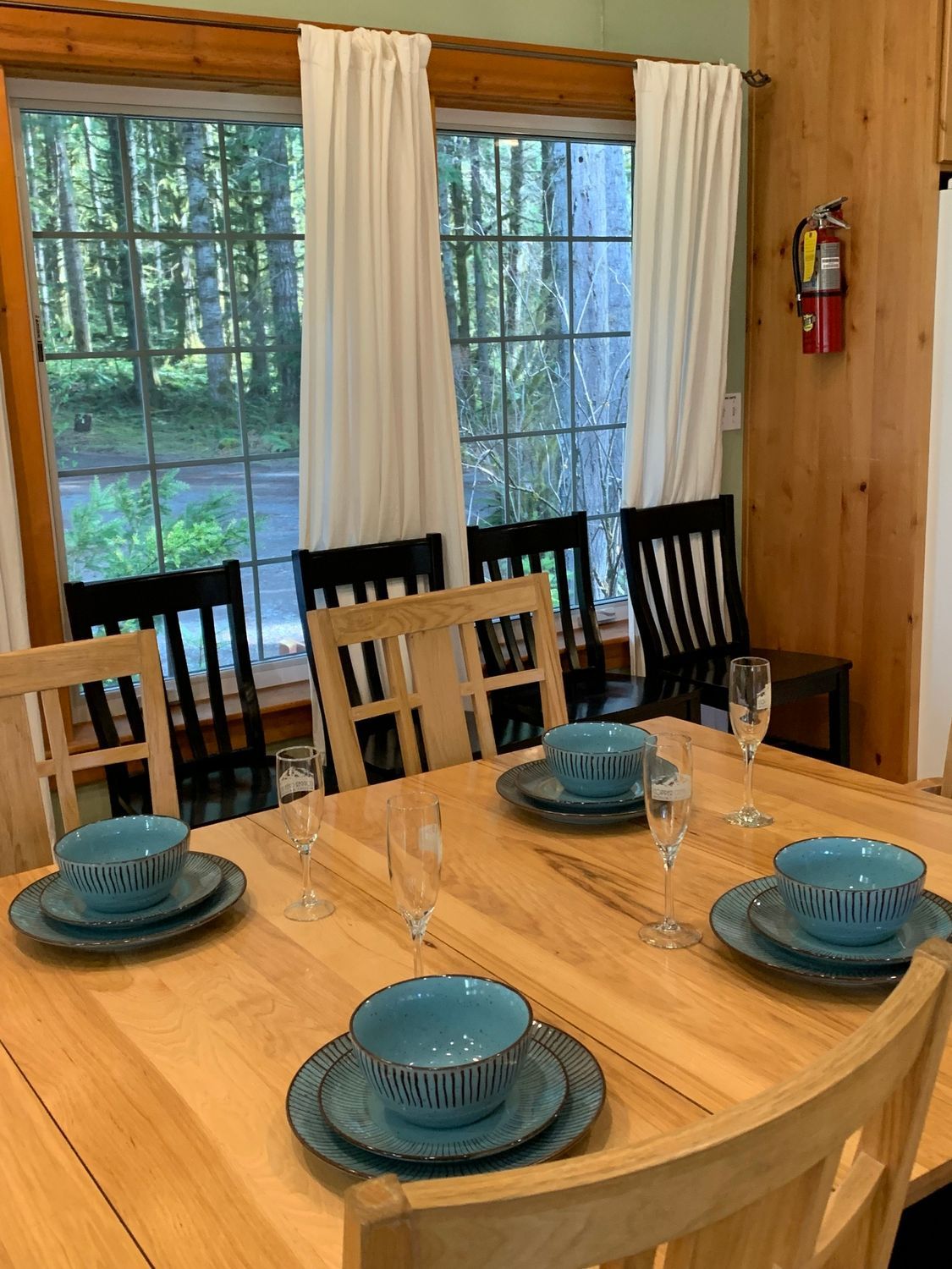 A dining room table with plates and bowls on it and a fire extinguisher on the wall.