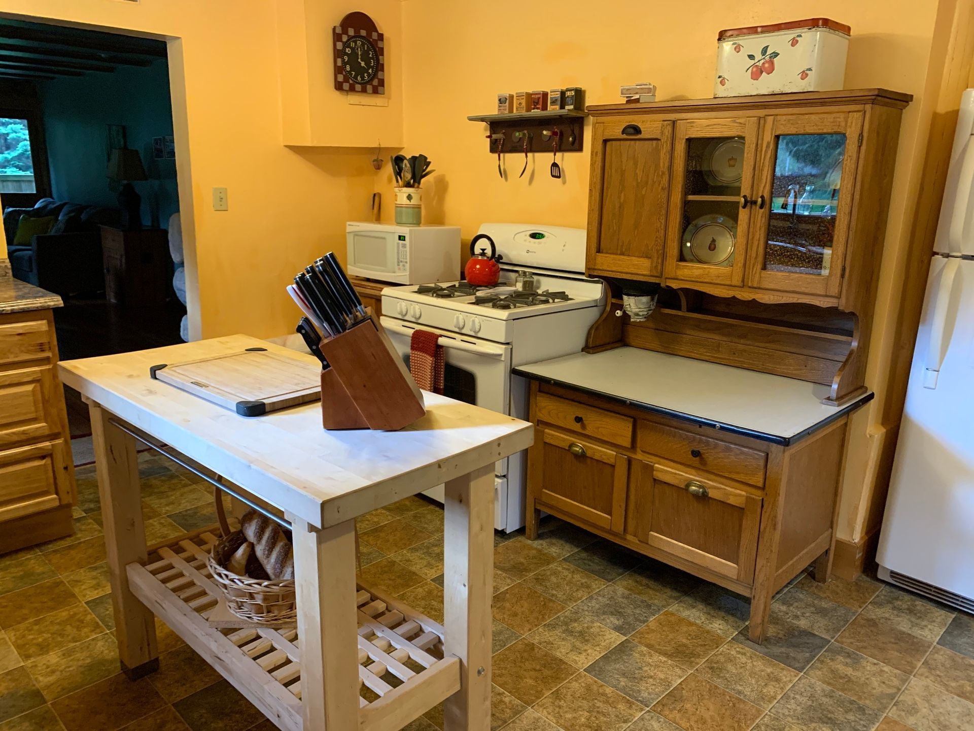 A kitchen with a stove , refrigerator , cabinets and a cutting board
