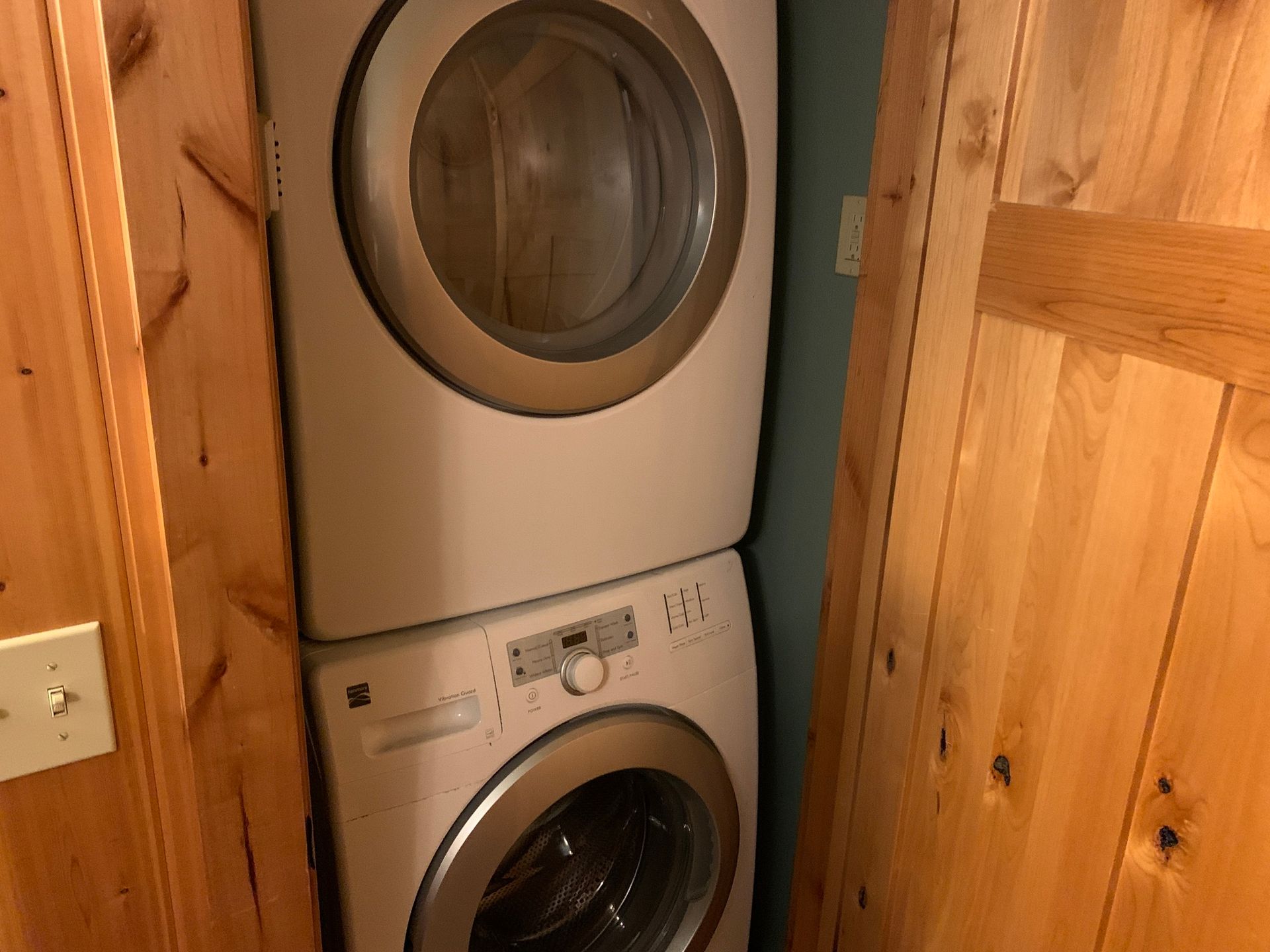 Stacked washer and dryer units inside a wooden closet.